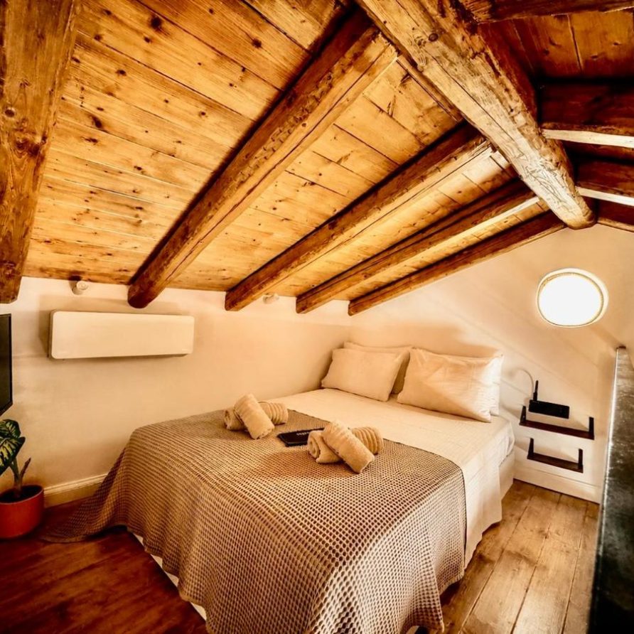 Double bed under the wooden ceiling of the loft